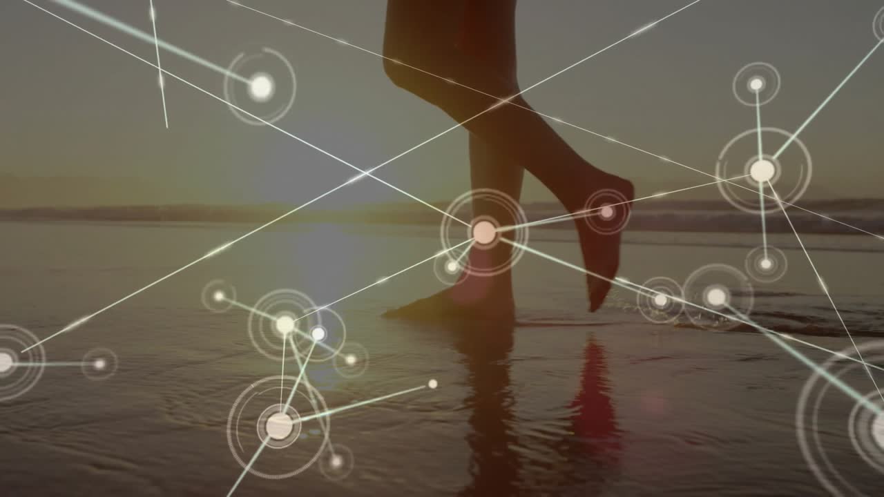 Mujer adentrándose en la marea que retrocede al atardecer y generando una superposición de red tecnológica digital luminosa.