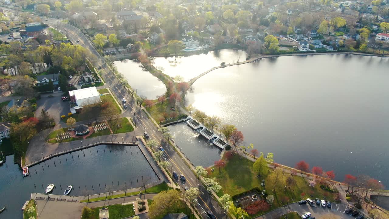 Aerial over West Babylon, New York township and Argyle Lake Park on sunny spring day