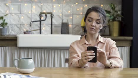 mujer usando un teléfono inteligente en la cocina