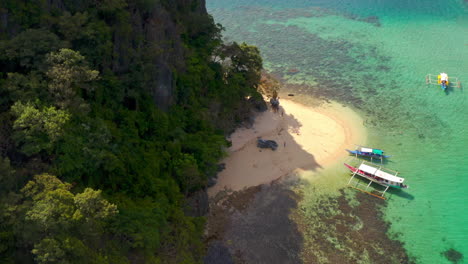 aerial view of tropical island beach and boats in clear turquoise waters