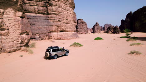 four-wheel drive vehicle driving through sahara desert in tassili n'ajjer national park at midday in algeria