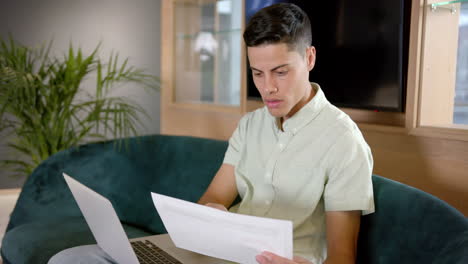 reviewing documents, man working on laptop while sitting on couch