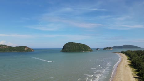 Picturesque-aerial-steady-footage-of-islands,-the-beach,-lovely-sky,-a-speeding-boat