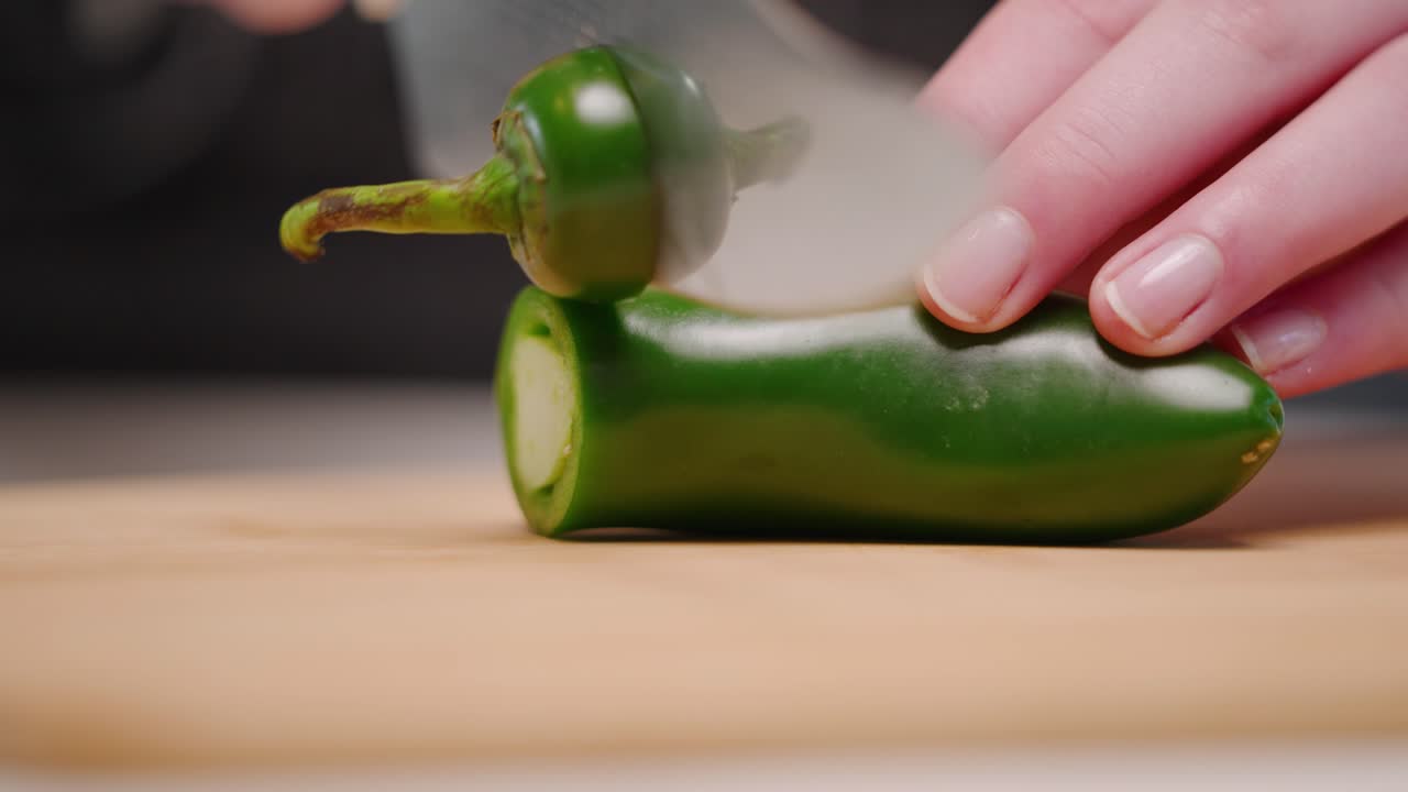 날카로운 칼로 전체 녹색 jalapeño 고추를 커팅 보드에 슬로우 모션으로 조각 더미로 자르는 백인 손