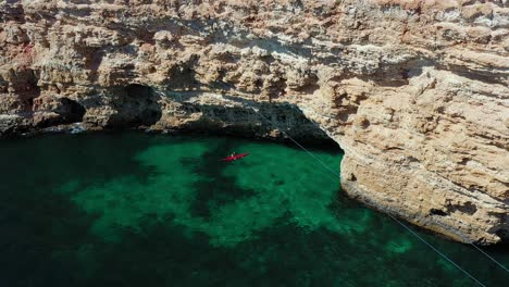 Adventure-and-exploration-as-a-person-in-a-kayak-paddles-towards-a-rockface-with-sea-caves