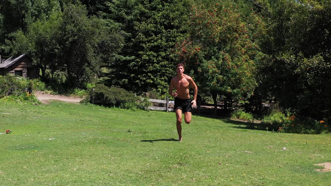 joven caucásico en forma atractiva haciendo ejercicio al aire libre con fondo de vegetación verde en 4k