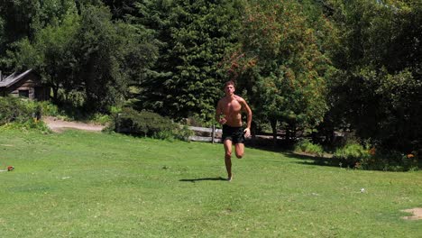 joven caucásico en forma atractiva haciendo ejercicio al aire libre con fondo de vegetación verde en 4k