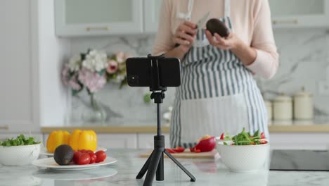 woman in apron records cooking vlog on cellphone