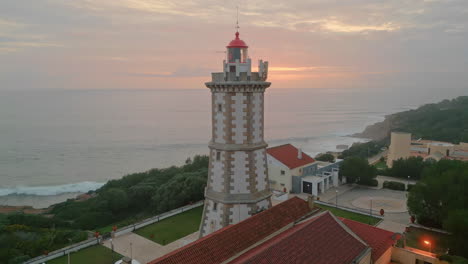 aerial shot lighthouse lighting to  ocean surface under evening sky.