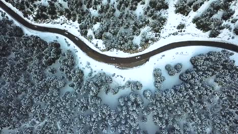 Drone-shot-over-an-icy-road-on-a-snowed-mountain-during-a-cold-winter-afternoon