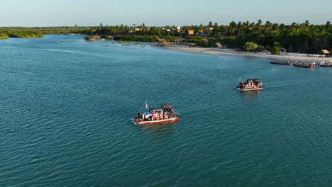 aerial orbiting view of small ferry boats carrying cars and people across a delta on the brazilian coast near jericoacoara