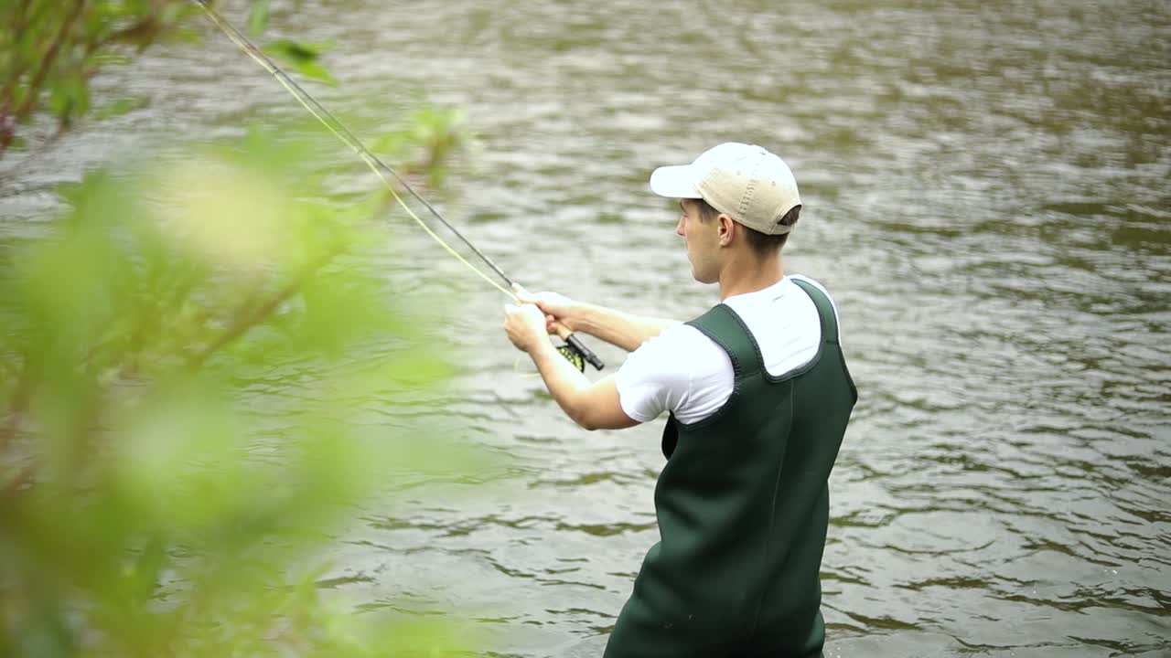 toma en cámara lenta de un pescador caucásico lanzando su anzuelo mientras pesca con mosca