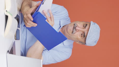 Vertical-video-of-Old-man-working-on-laptop-throws-files-angrily.