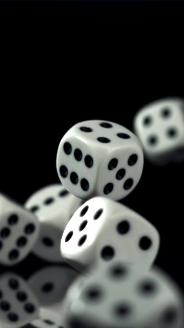 Hvide terninger falder og hopper i slowmotion på en sort overflade