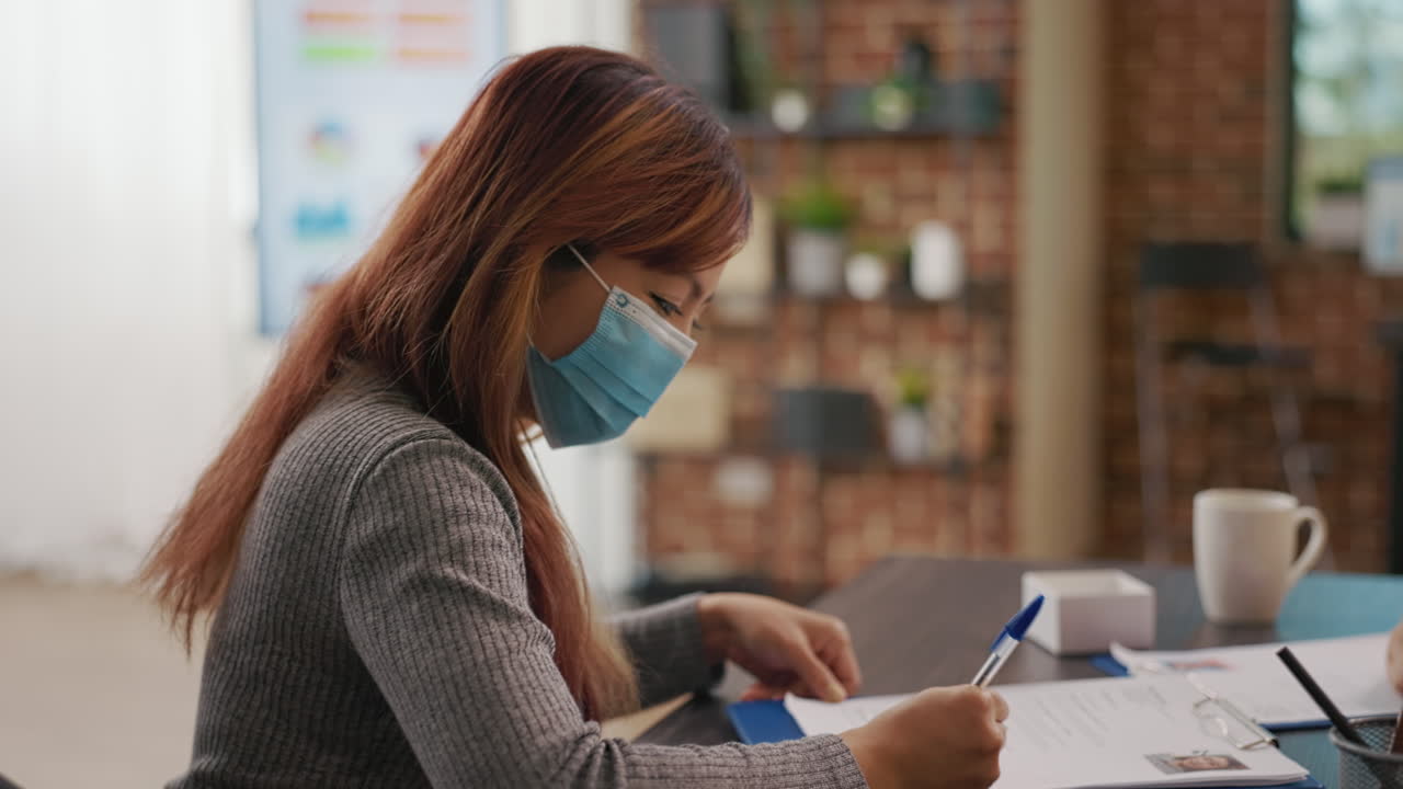 Asian woman signing hiring contract at job interview with business employee