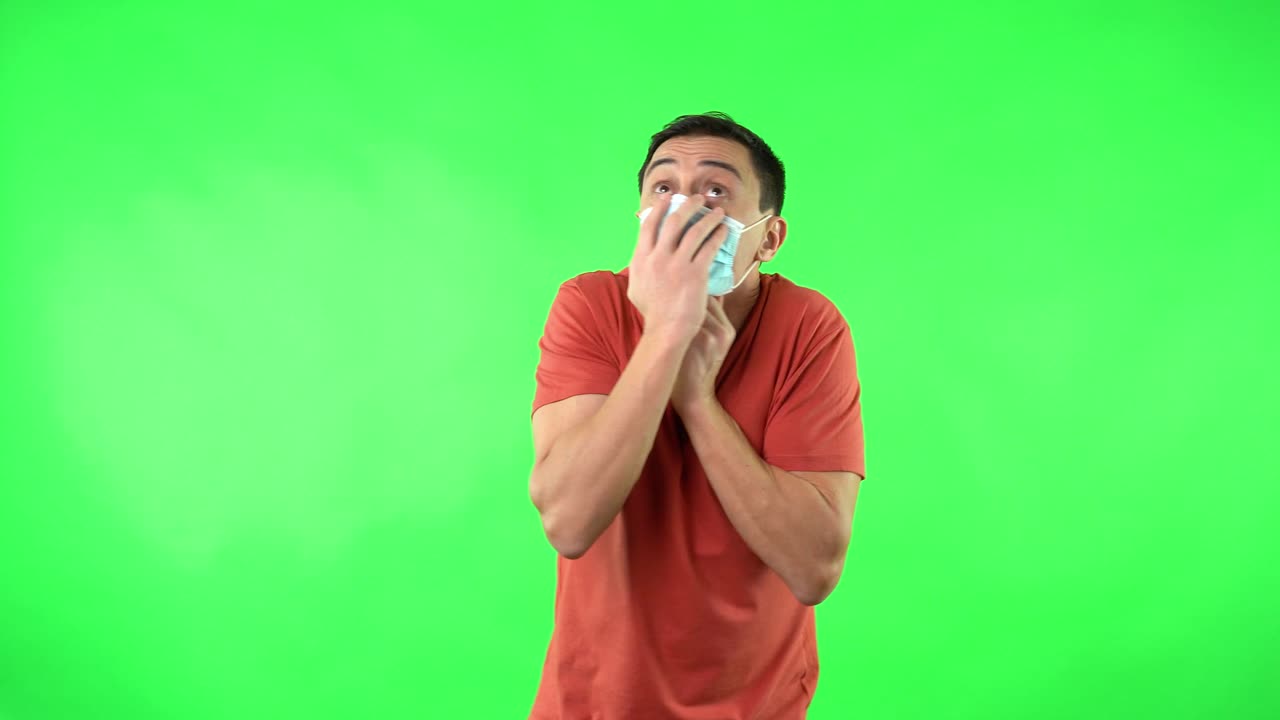 Man in surgical mask looking fearful and anxious on green screen