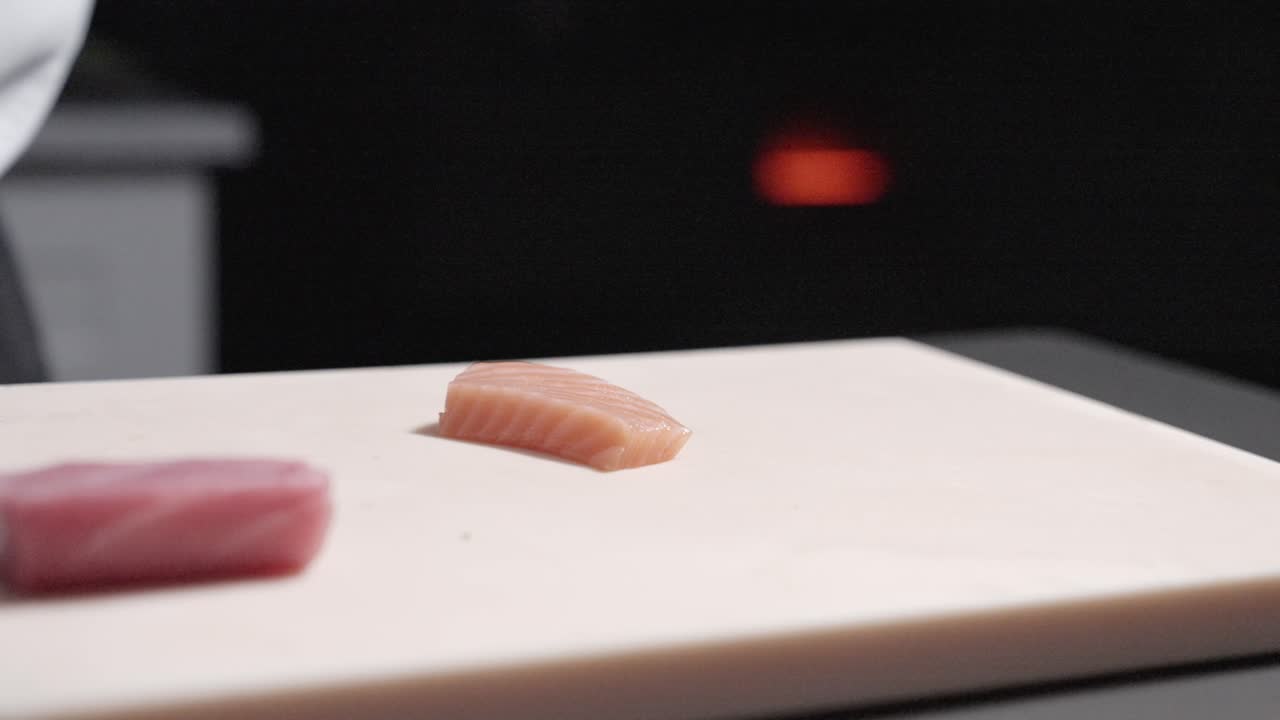 A static shot of salmon being sliced into pieces, showcasing the preparation process for sushi. Perfect for highlighting sushi ingredients, culinary techniques, and Japanese cuisine.