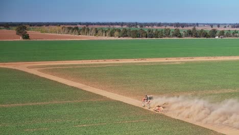 Aerial-view-of-tractor-and-small-grader-near-a-country-road-with-truck-beyond