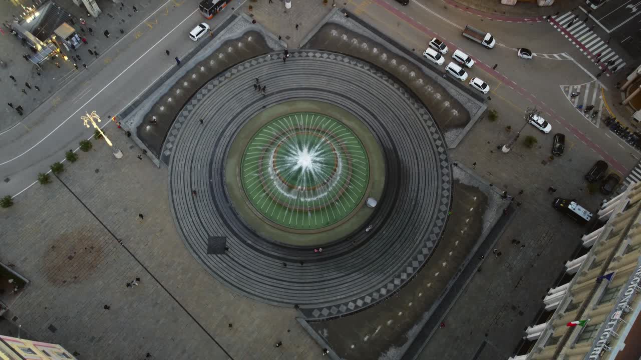 Historic Genoa city downtown plaza with fountain, lit by sunset light.