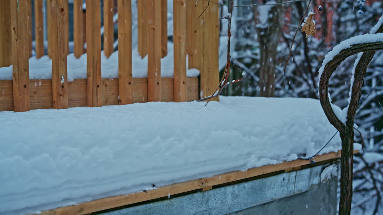 First snow gently accumulating on a backyard deck of a residential house during an early winter seasonal transition. Lateral movement