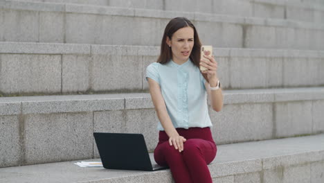 Mujer-De-Negocios-Que-Tiene-Video-Chat-En-Un-Teléfono-Inteligente.-Gerente-Usando-El-Teléfono-Al-Aire-Libre