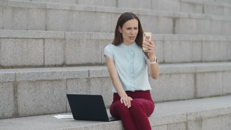 mujer de negocios que tiene una videochat en un teléfono inteligente. gerente que usa el teléfono al aire libre