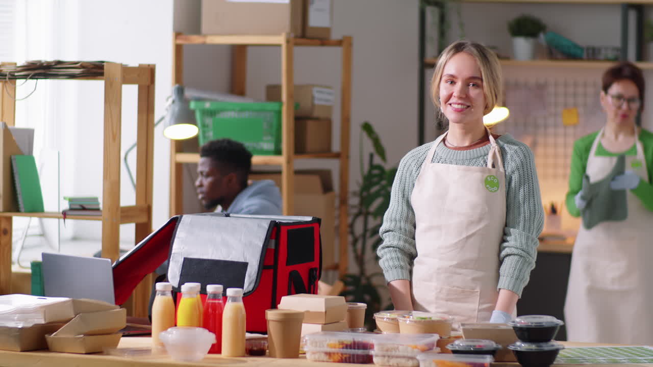 retrato de una mujer joven feliz trabajando en la cocina de entrega de alimentos