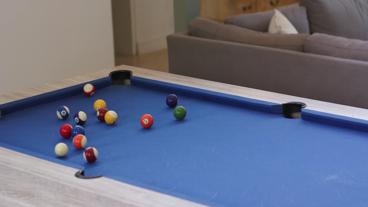 Man steadying cue ball on pool table before striking, initiating break to start game at home