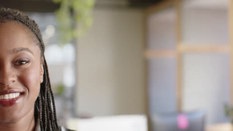 Half-portrait-of-happy-african-american-businesswoman-smiling-at-office,-copy-space,-slow-motion