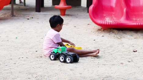 young boy enjoys playing with a green toy truck