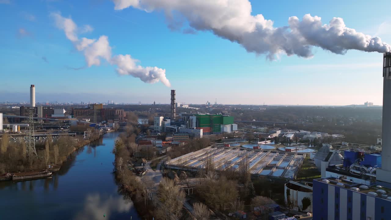 Waste to energy plant emitting smoke from its chimney, located near an urban area, environmental impact of waste. panorama overview drone