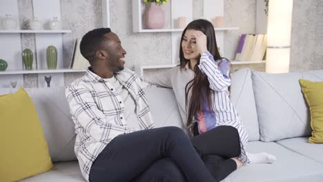 una joven pareja sonriente y diversa pasando tiempo juntos en casa, tomados de la mano.