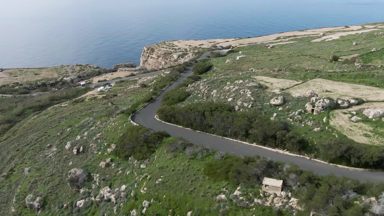 Distant View Of A Car Driving Fast On The Uphill Road Track Overlooking The Big Blue Sea - Aerial Shot