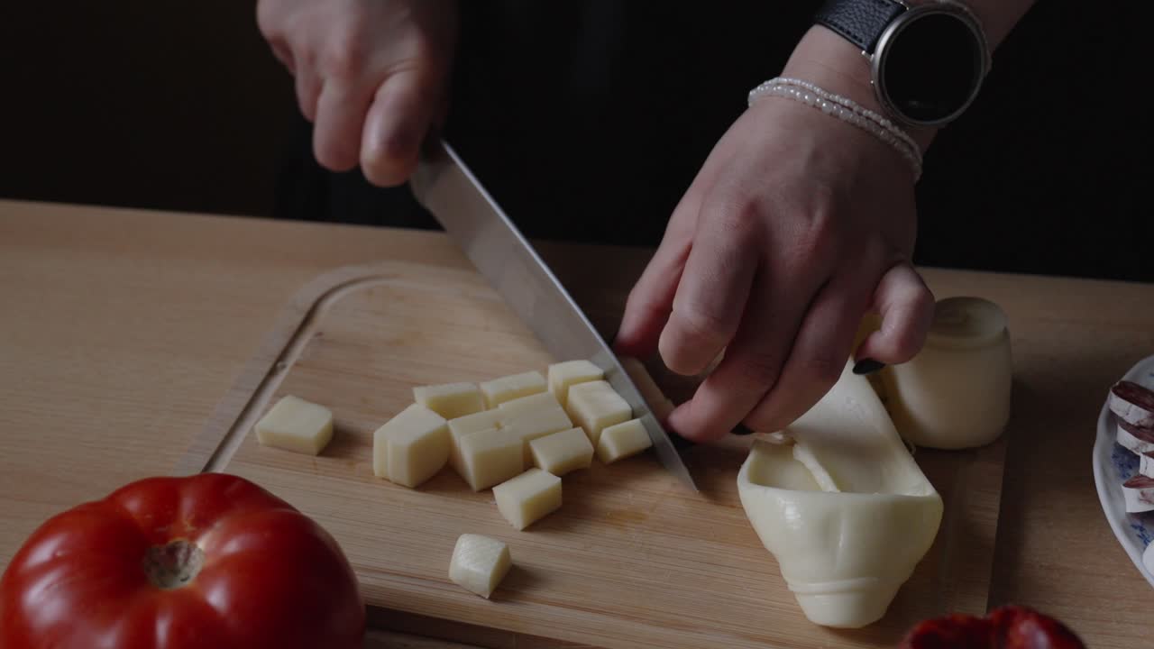 A popular type of cheese in Europe, especially in villages. Slicing the delicacy to serve with meat products. Girl in the kitchen