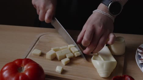a popular type of cheese in europe, especially in villages. slicing the delicacy to serve with meat products. girl in the kitchen
