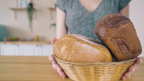 woman puts handmade bread in basket on wooden table closeup