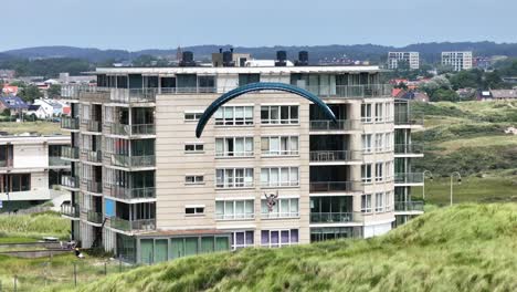 paragliding over apartment building in coastal town