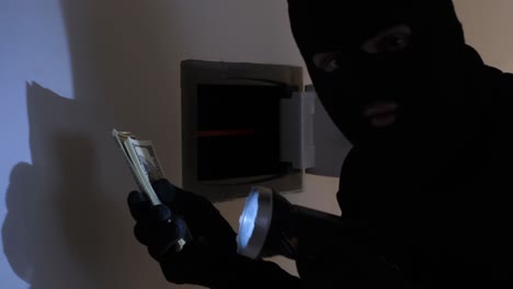 a burglar in a black balaclava opened a safe in a house and stole dollars criminal violation. a burglar in a black balaclava opened a safe in a house and stole dollars. criminal violation. security alarm for safety and security