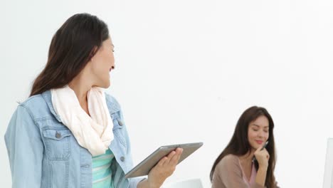 Creative-businesswoman-using-her-tablet-with-coworker-behind-her