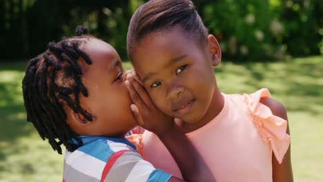 little boy whispering a secret to his sister