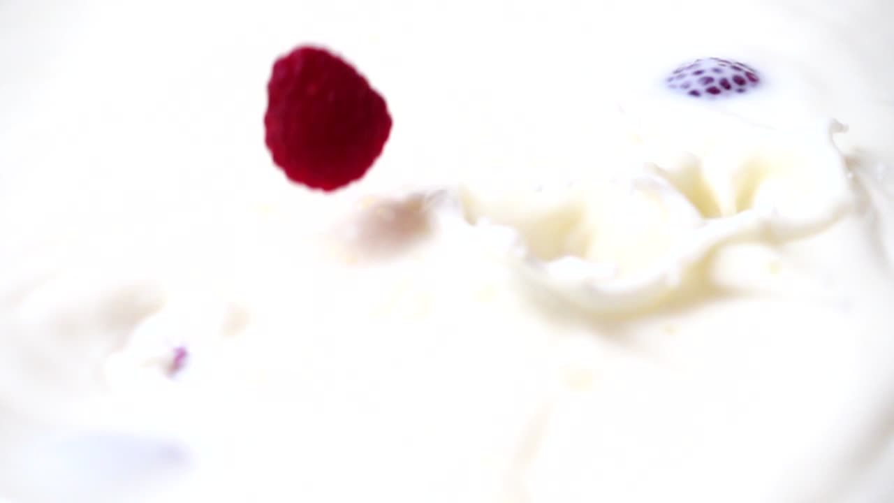 Falling of raspberry in milk. Slow motion. Shooting of fruit. Slow motion