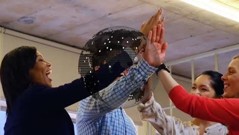 animation of spinning globe over diverse colleagues high fiving each other at office