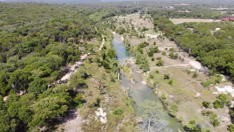 Flying-over-the-river-and-trees,-slow-decent-towards-the-swimming-area---Aerial-footage-of-the-Blanco-river-in-Wimberly,-TX