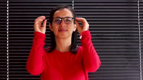 Young-woman-putting-on-eyeglasses-and-taking-them-off,-medium-close-up