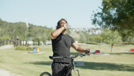 tired man with artificial leg drinking water during cycling