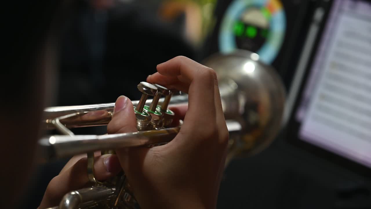 트럼펫을 들고 있는 학생이 손을 위아래로 움직이며 비트를 이끄는 교사로서 음악을 읽는 동안 트럼펫 레슨