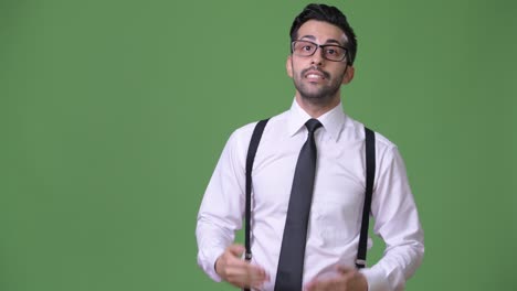 joven empresario persa barbudo y guapo contra un fondo verde