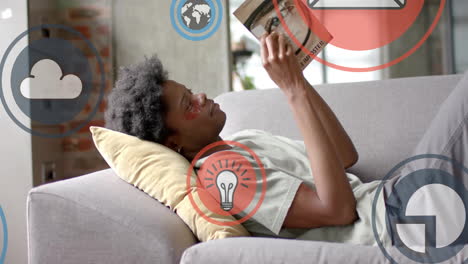 animación de procesamiento de datos sobre hombre afroamericano leyendo un libro en el sofá