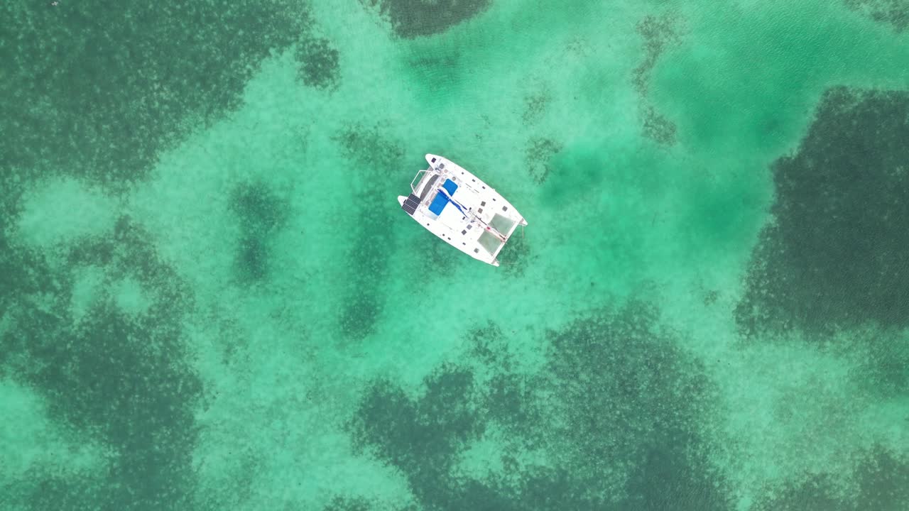 drone vista en belice volando todavía sobre el caribe mar oscuro y azul claro vista superior arrecife de coral de aguas poco profundas y un barco