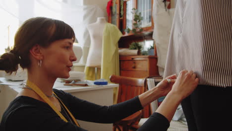 dressmaker pinning edge of shirt on female client